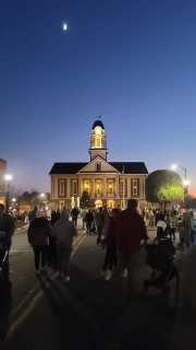 Standing in the street with other festival goers looking at the courthouse in the dusk.