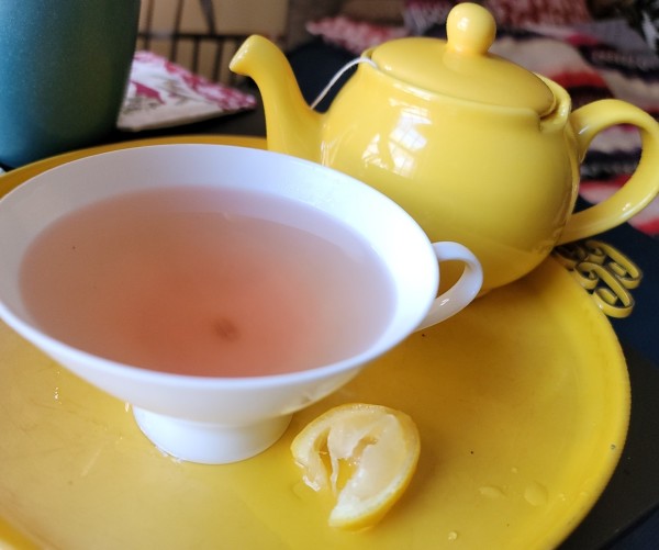 Kenyan Purple Tea in a wide, shallow tea cup on a tray with a small teapot